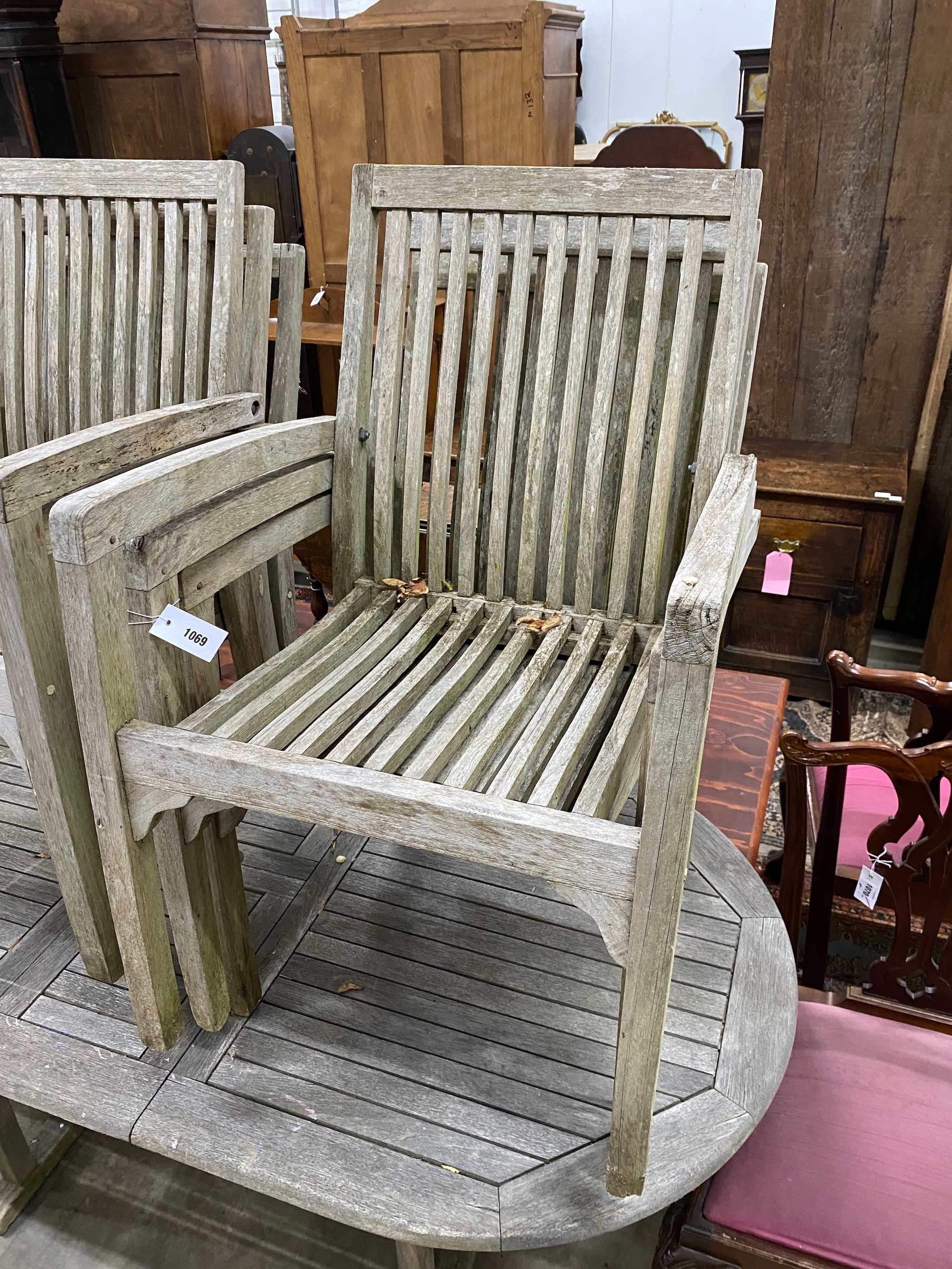 A weathered teak extending garden table, 180cm extended, width 90cm, height 74cm and six stacking chairs